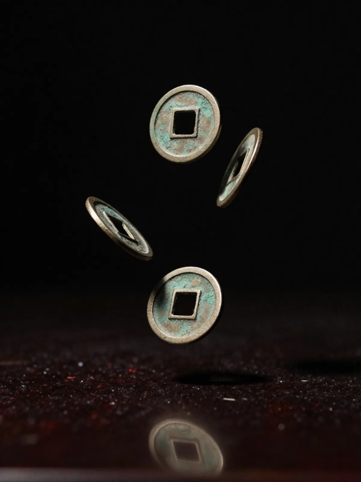 Three bronze coins frozen mid-throw above a dark lacquered surface