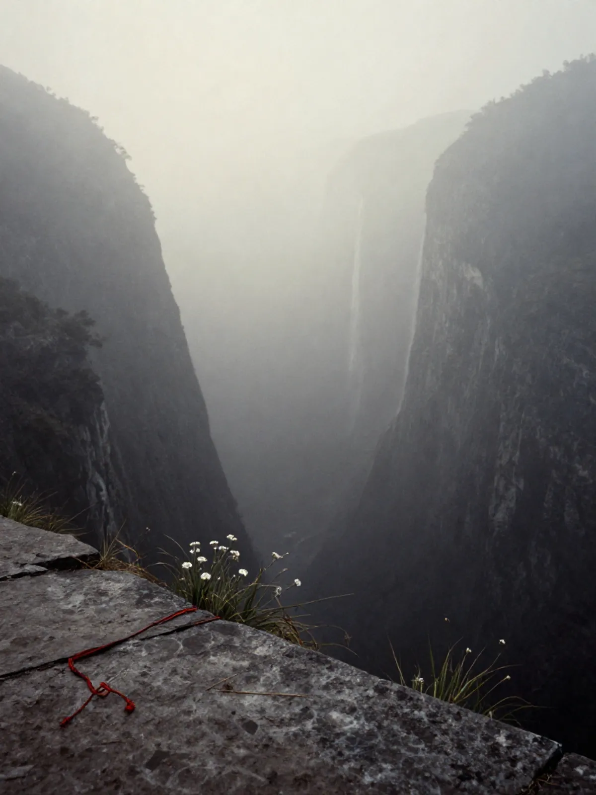 A misty valley at dawn, a waterfall descending into silver haze