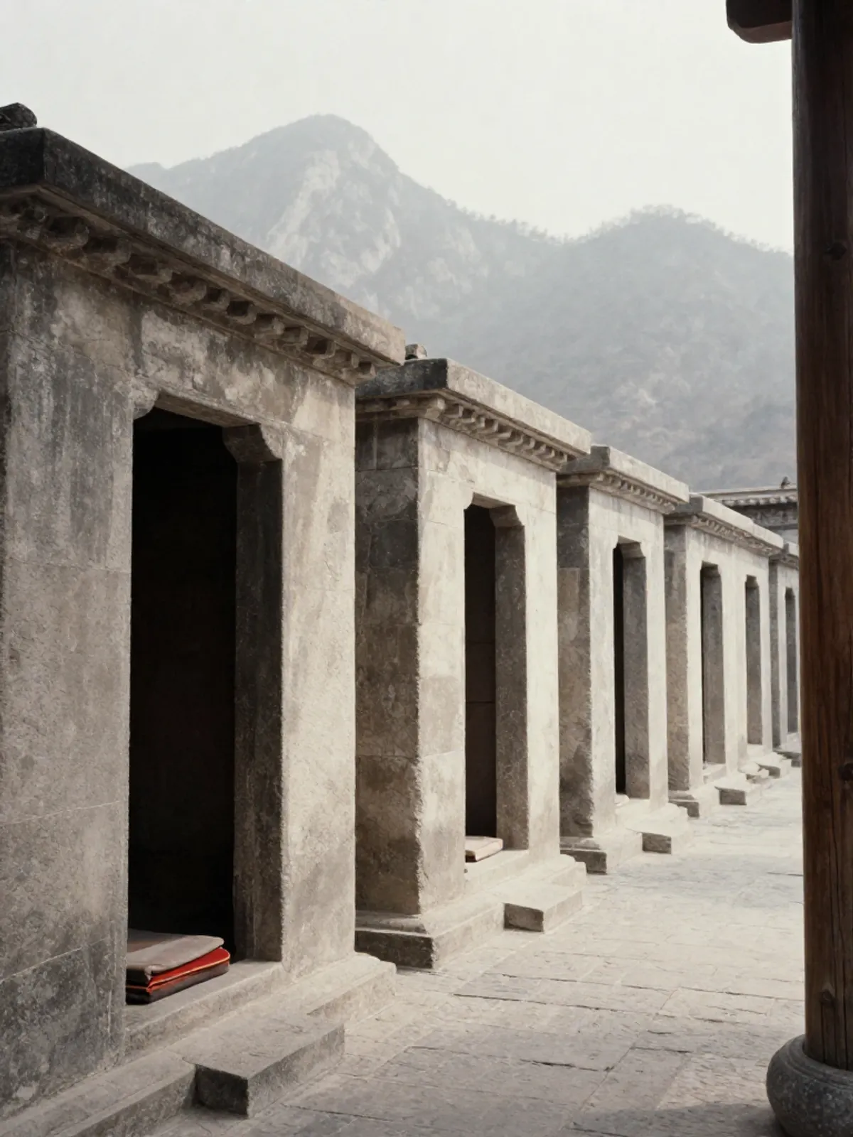 Stone meditation cells in a mountain monastery, bare interiors, distant peaks beyond